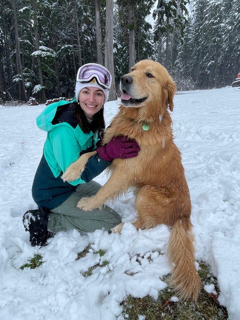 Madison kneeling in fresh snow with her golden retriever
